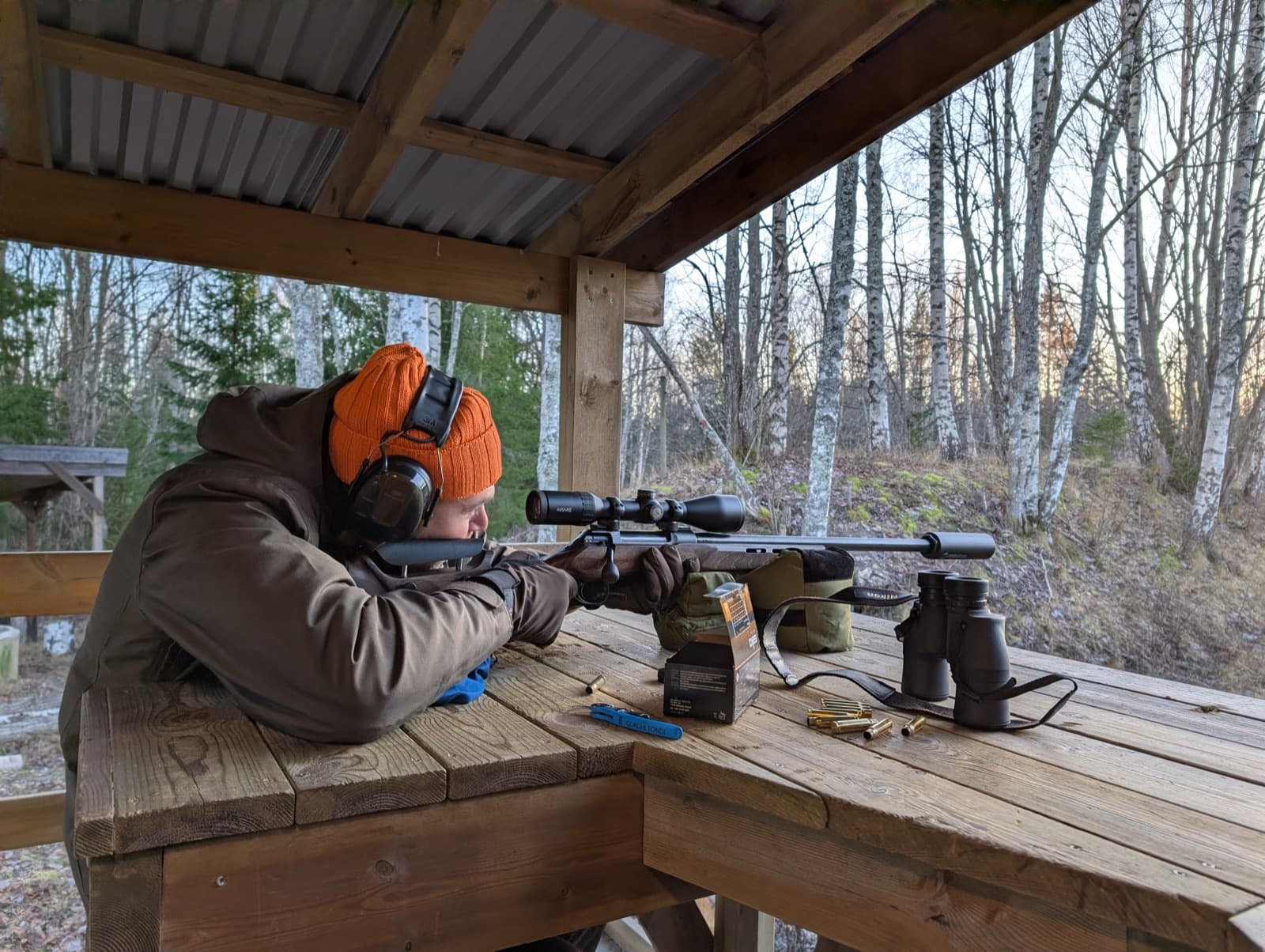 Jägare skjuter in ett kulgevär med kikarsikte från skjutbänk på skjutbana